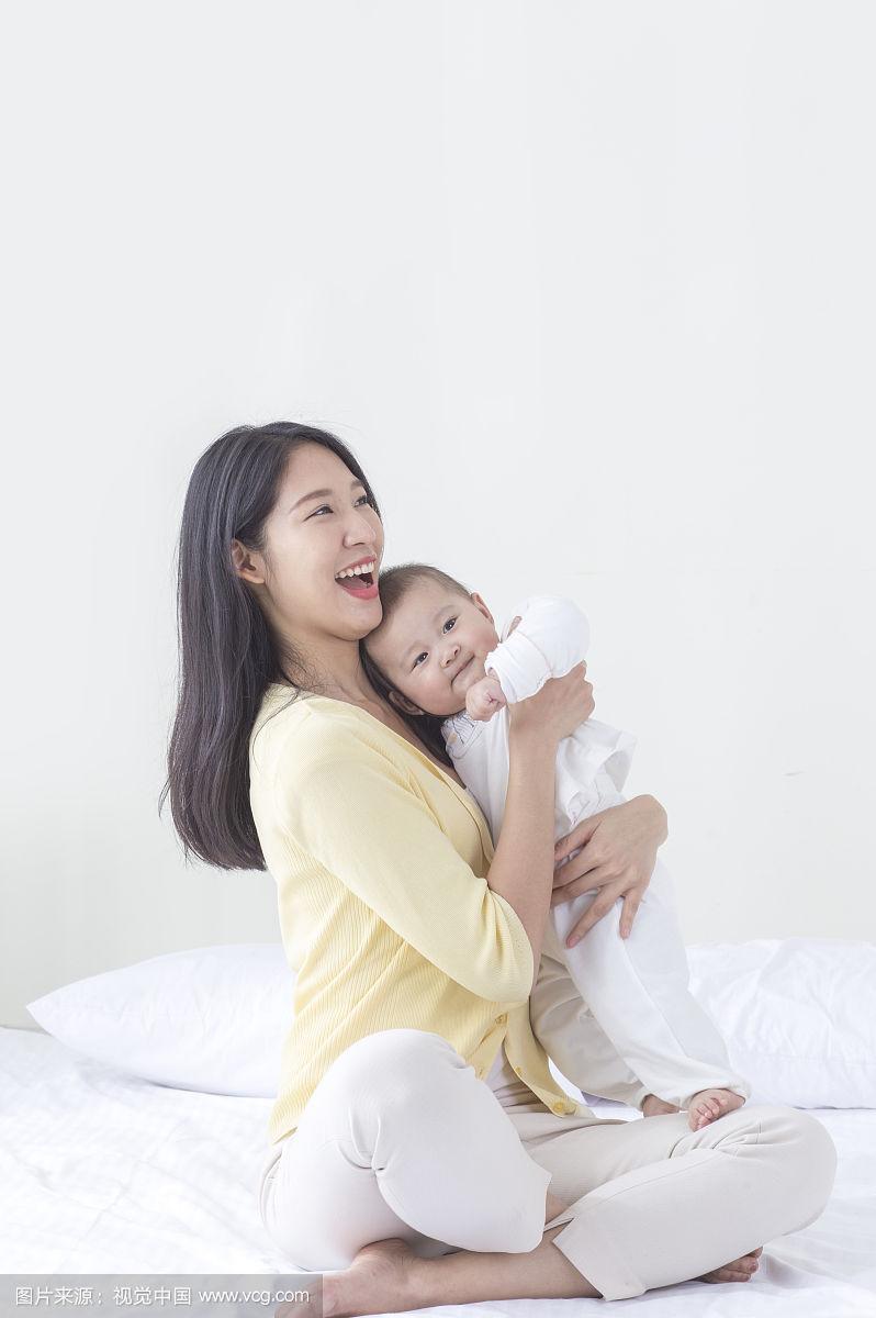新手妈妈抱夜醒宝宝坐在卧室场景图