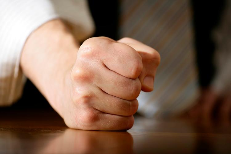年轻人在工位上攥紧拳头压抑情绪的实拍图