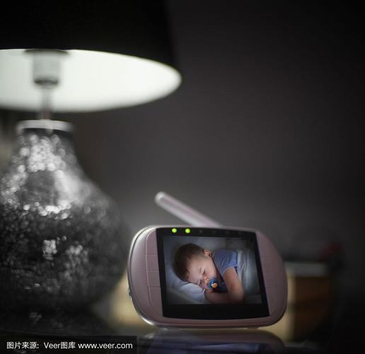 疲惫的母亲在凌晨透过婴儿监视器查看宝宝