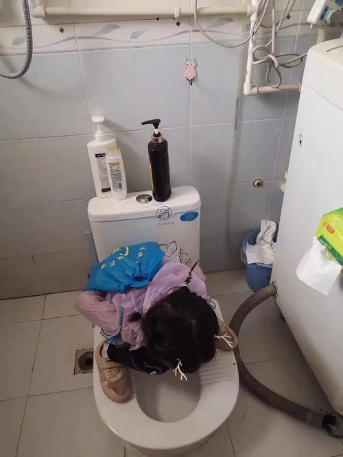 小孩蹲在卫生间马桶边检查漏水的真实居家场景