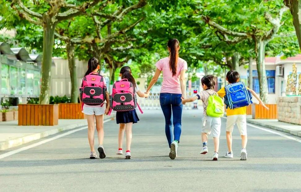 家长和孩子边唱边上幼儿园背影