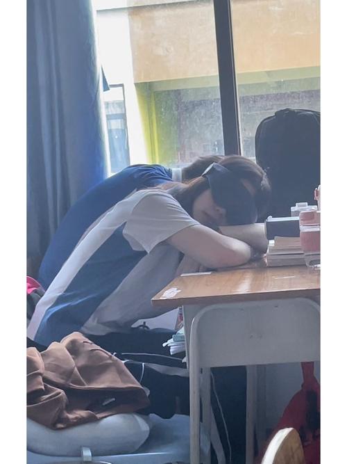 高中教室后排学生趴在桌上沉默的侧拍