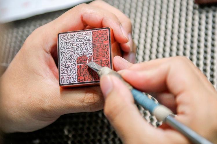 学生篆刻社团成员在教师指导下雕刻印章