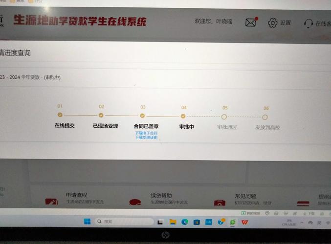 大学生坐在电脑前操作助学贷款系统界面