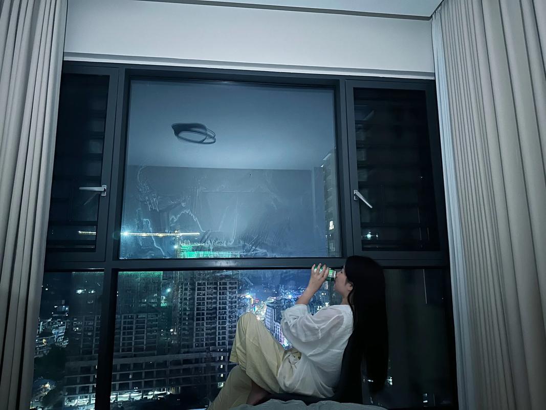 女生独自在夜晚窗边写日记反思情感的画面