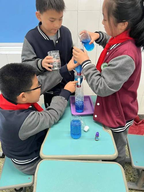 小学科学课上教师和学生观察蓝水表面张力实验的课堂场景