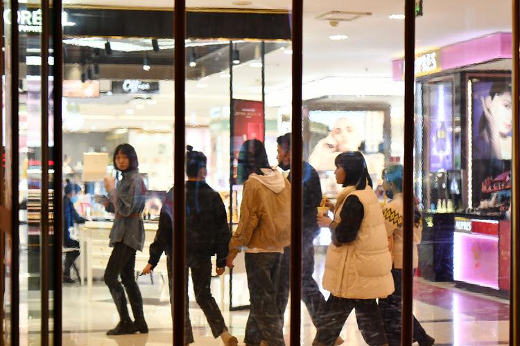 透过商店玻璃橱窗反射拍摄街头行人