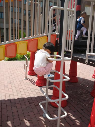 小学生蹲在单元楼台阶上调整石板弹珠滑道实拍