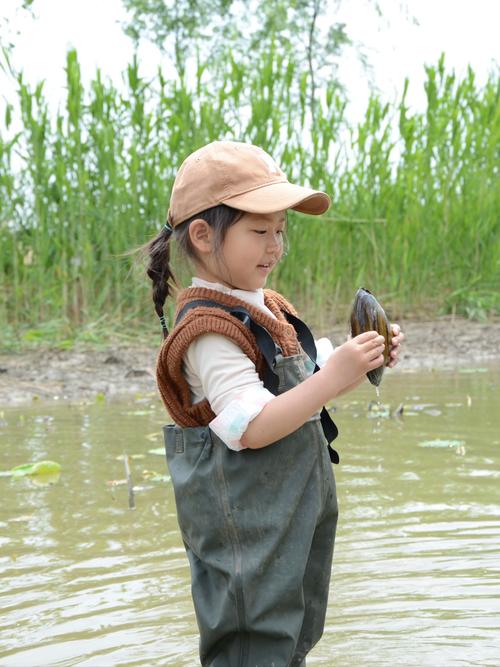 南京鱼嘴湿地岸边蹲在泥坑边观察豆娘的小学生
