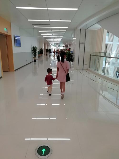 小学走廊里小男孩扶着术后妈妈慢慢走的侧影