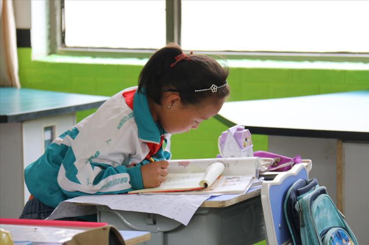 乡村小学走廊上学生蹲坐写作业的实拍
