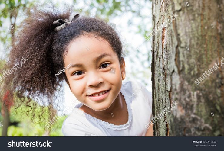 little girl hiding behind hands peeking guilty