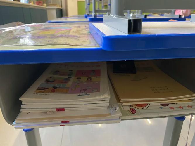 初中教室不同颜色分层练习册堆在课桌角