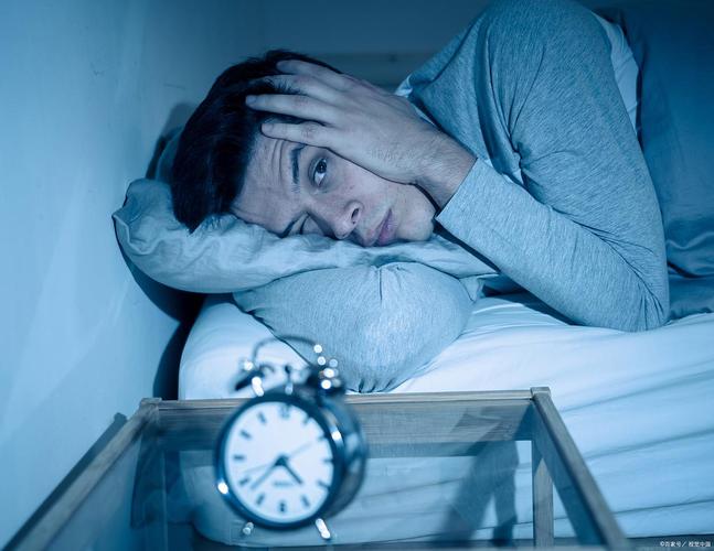 慢性失眠患者躺在床上盯着床头时钟焦虑的实拍图