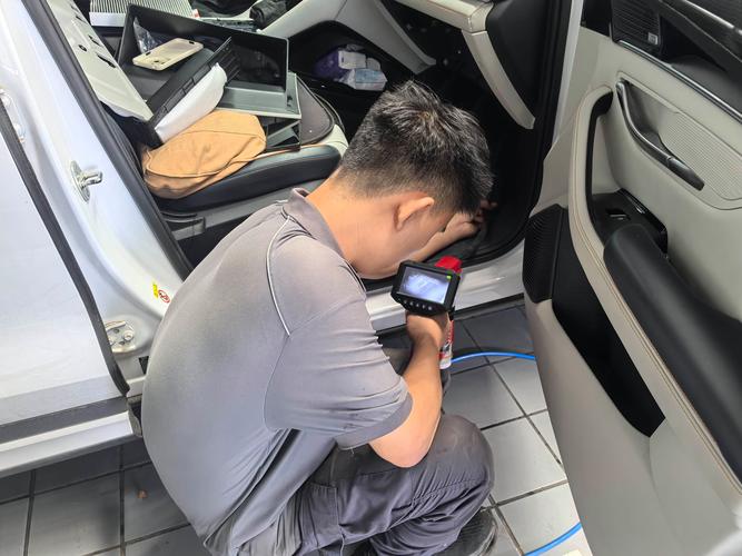 汽修技师蹲在副驾脚窝插OBD诊断设备实拍