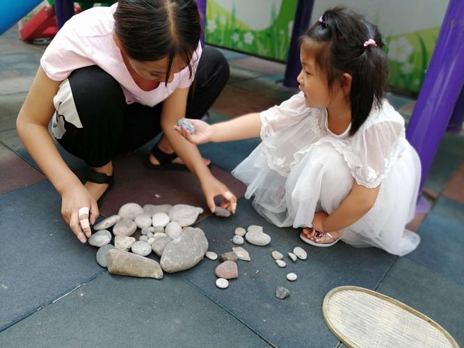 孩子在家客厅地板上摆放分类好的户外捡拾岩石的实拍图
