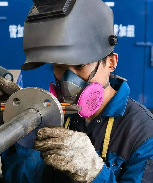 焊接车间工人佩戴防尘口罩配合局部排风臂作业实景