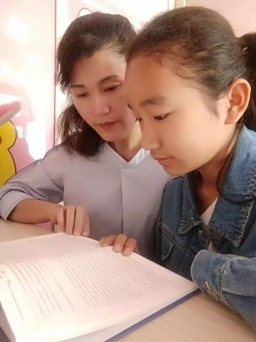 妈妈和小学高年级孩子趴在书桌边指着课本聊天