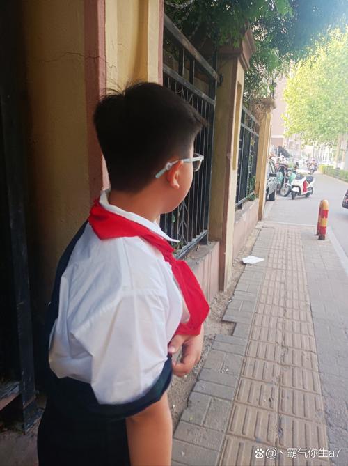 小学走廊上穿蓝校服的小男孩攥着衣角红耳朵