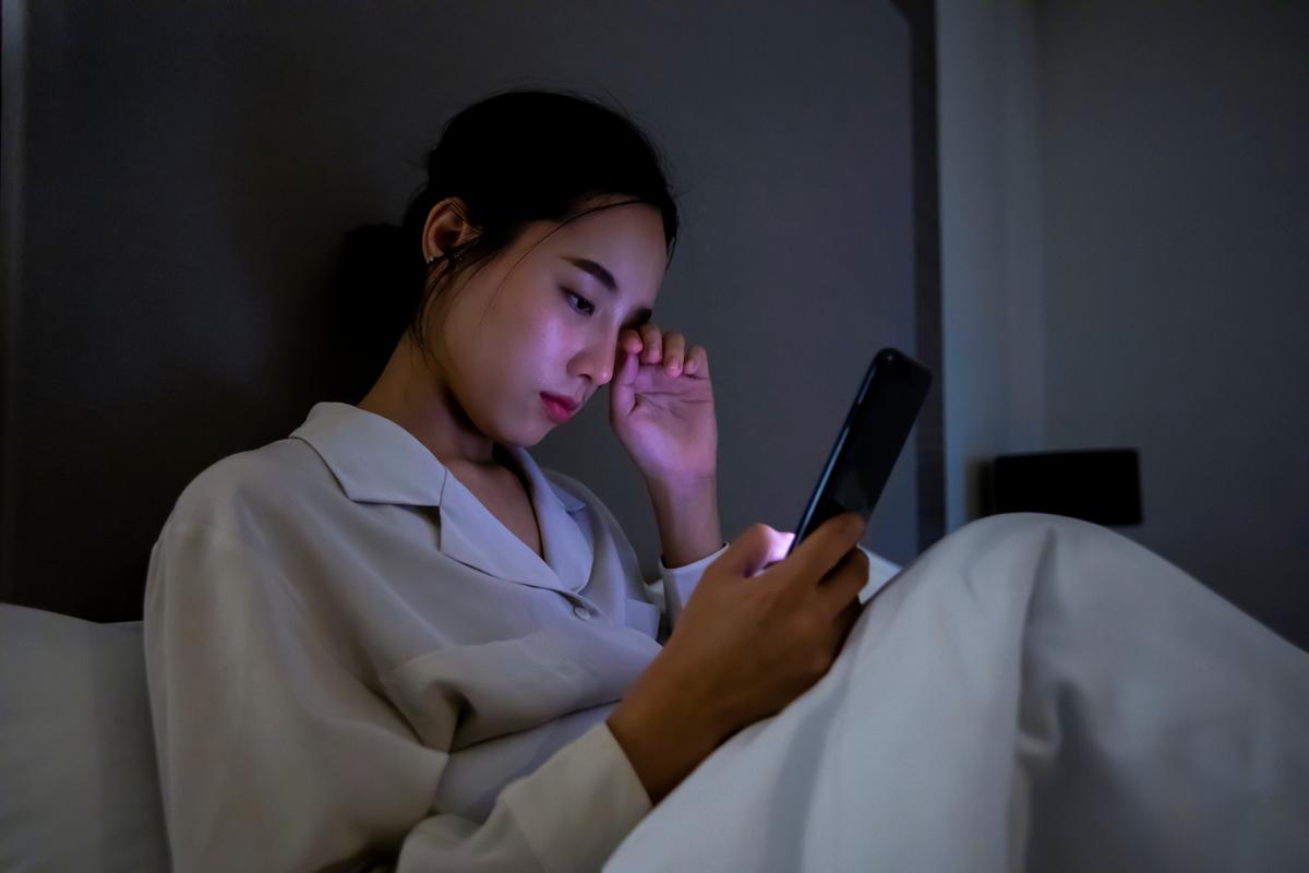 熬夜后对着手机打卡界面皱眉头的年轻女生