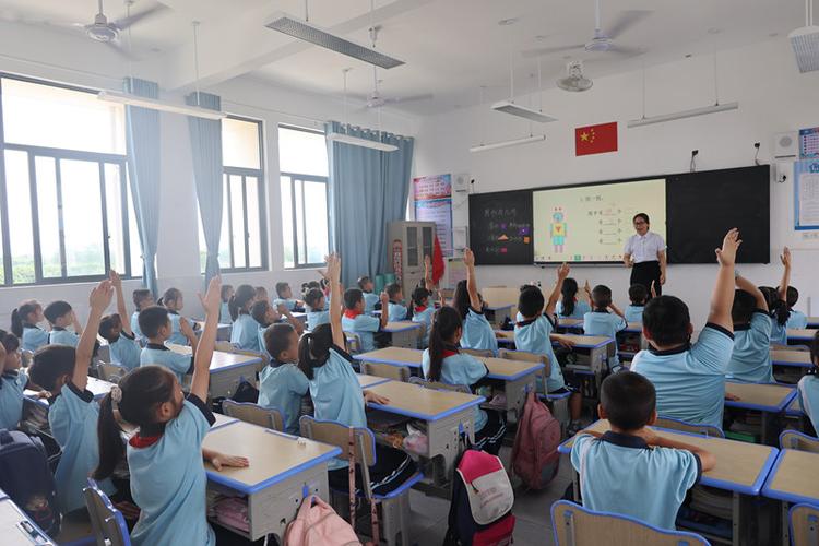 小学课堂学生举手抢答教师提问场景