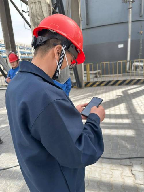 工业职工在厂车上用手机看育儿短视频 旁边放着工作安全帽