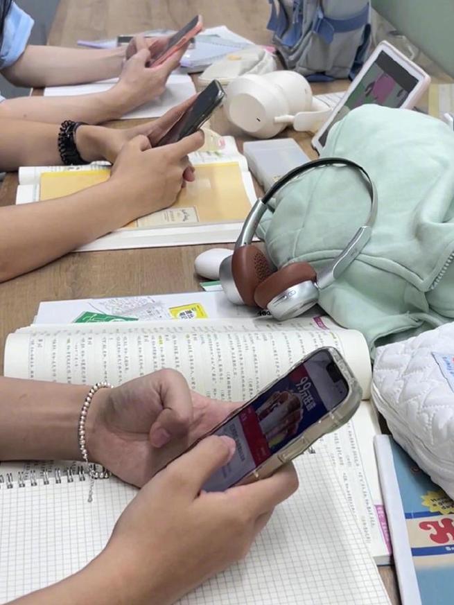 学生书桌学习时旁边手机亮起分心场景