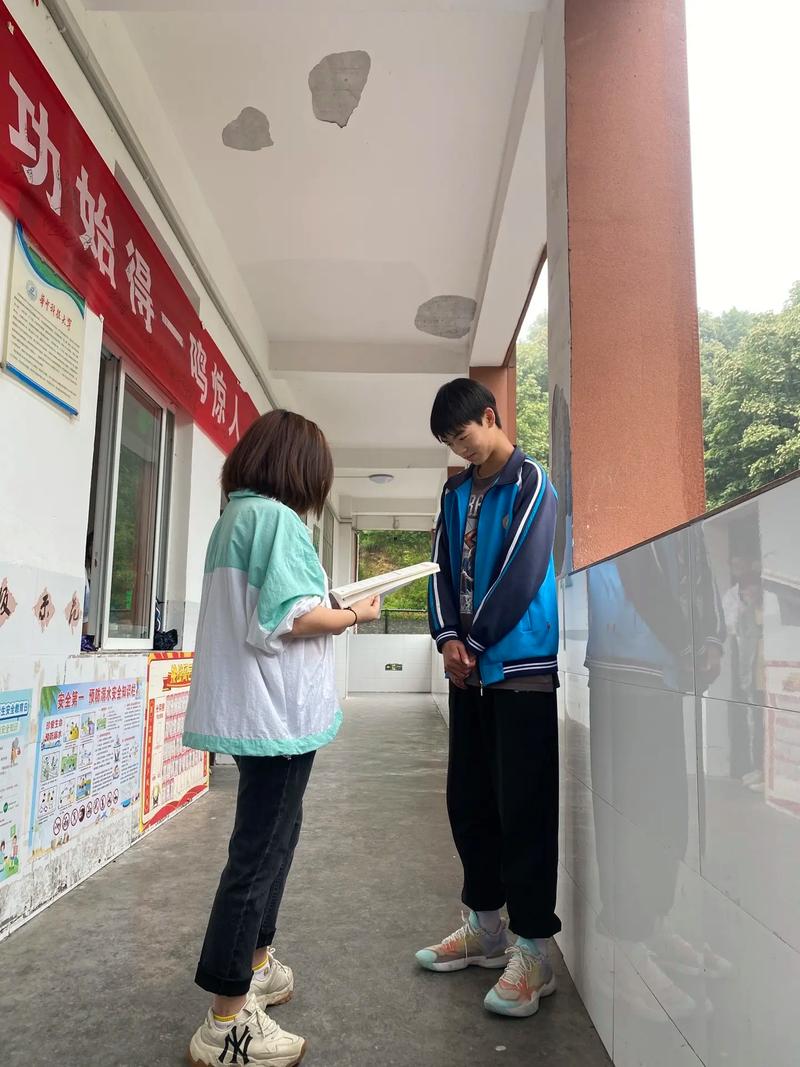 中学班主任靠在走廊栏杆和学生并肩站立的日常场景
