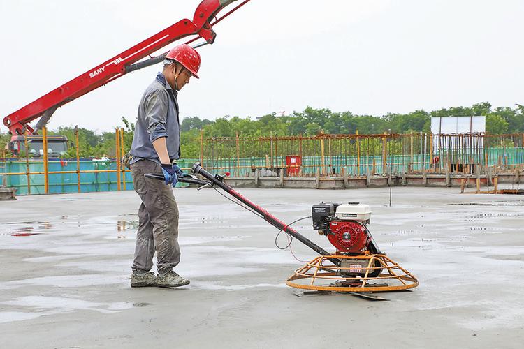 工人手持铁抹子进行水泥地面压光施工特写
