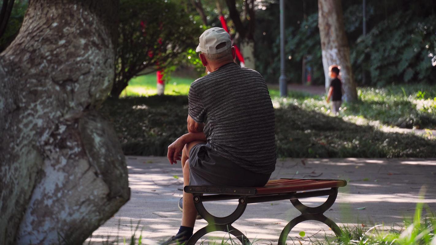 公园长椅上面朝林荫路的人发呆背影