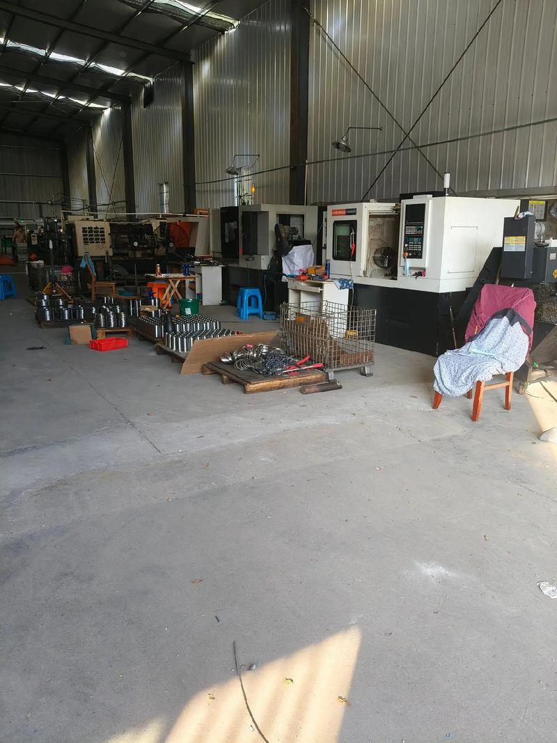 杂乱的小型机械加工车间内景，工人正在调试旧加工中心