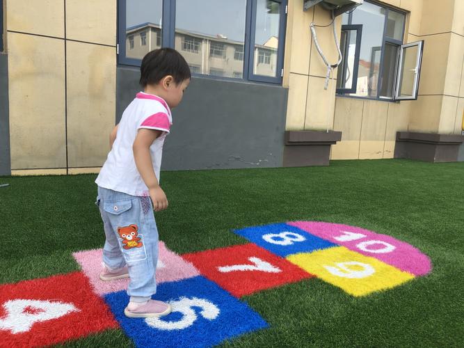 幼儿园小朋友在小区步道防滑垫和大理石交界处蹭脚玩