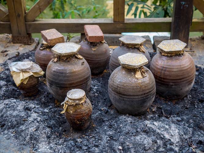石台农家火塘边搭着竹架温米酒的陶制酒壶