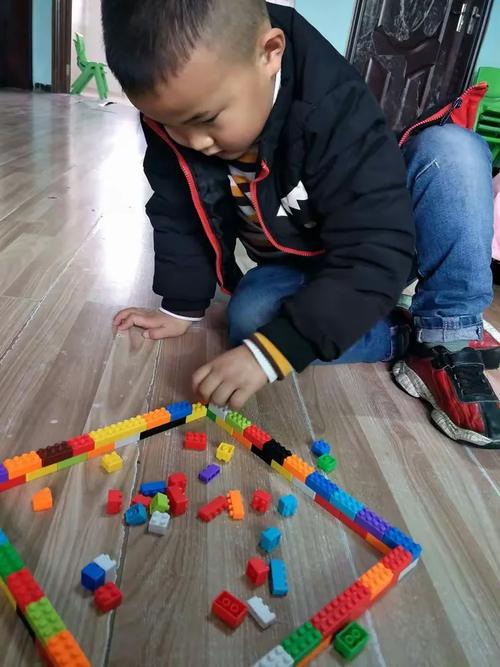 儿童蹲在小区楼下玩旧积木场景