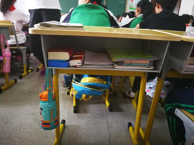 中学校园里学生在新换的大容量课桌抽屉里放保温杯和练习册