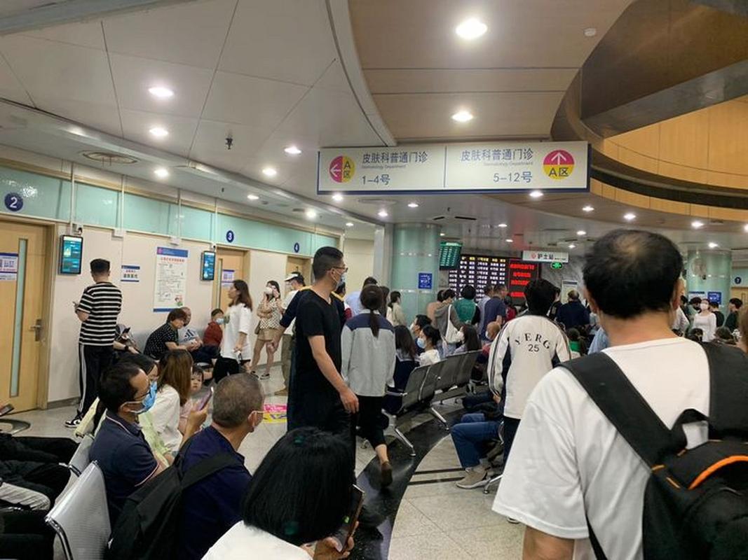 年轻人坐在体检中心走廊攥着体检报告的实拍图