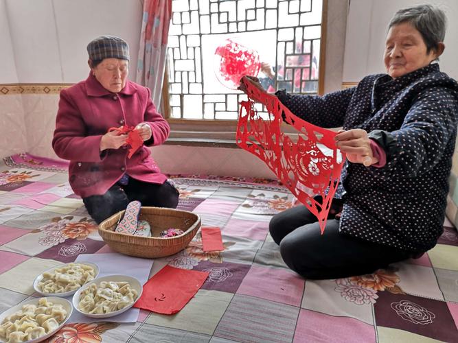 南漳肖堰镇农妇在堂屋门口剪红纸窗花