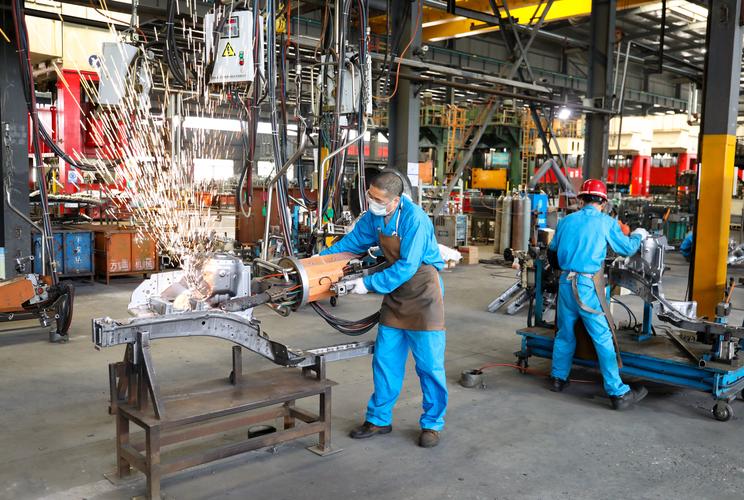 机械加工厂车间工人帮同事调整工具