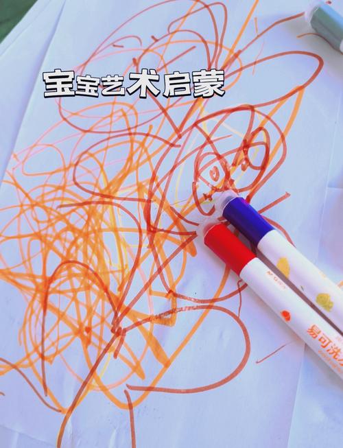 2岁宝宝拿着粗蜡笔在爬行垫的大画纸上涂鸦的实拍