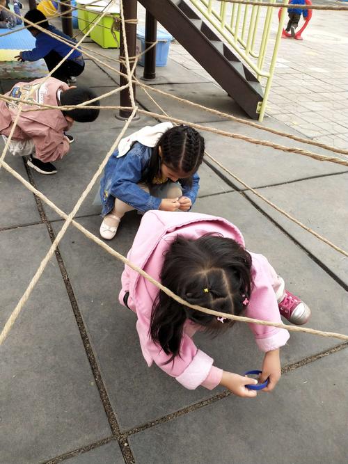 小孩蹲在阳台绕旧棉线球的日常场景