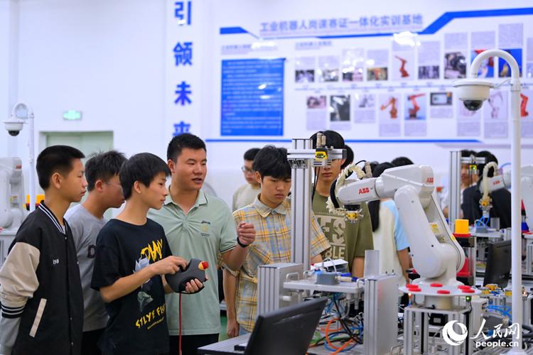 现代学徒制学生与师傅在工业机器人工作站