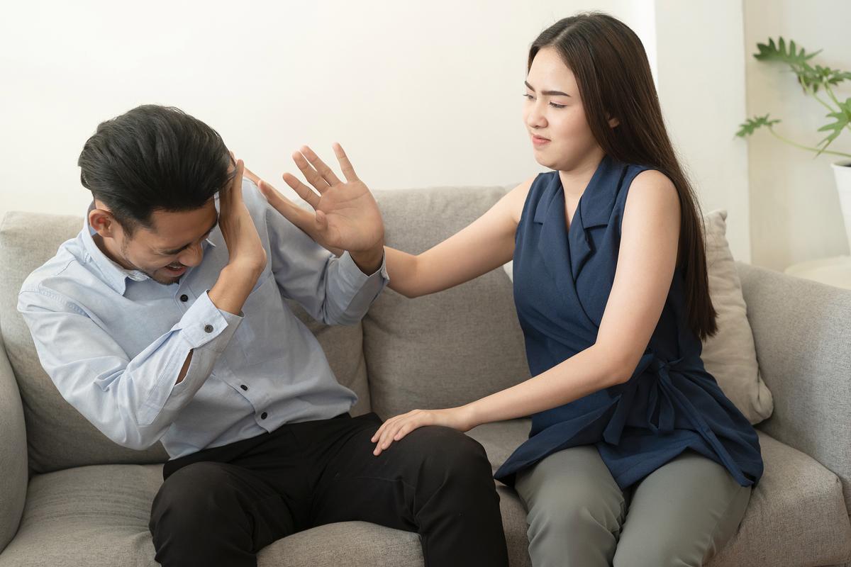 夫妻在沙发上沟通,丈夫面带困惑,妻子情绪激动