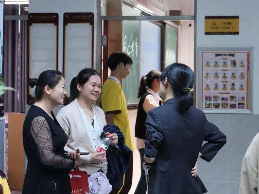 家长和班主任在学校走廊站着轻声交流的实拍场景