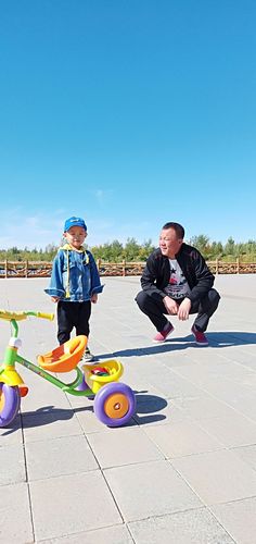 爸爸蹲下来和幼儿平视玩耍的亲子互动场景