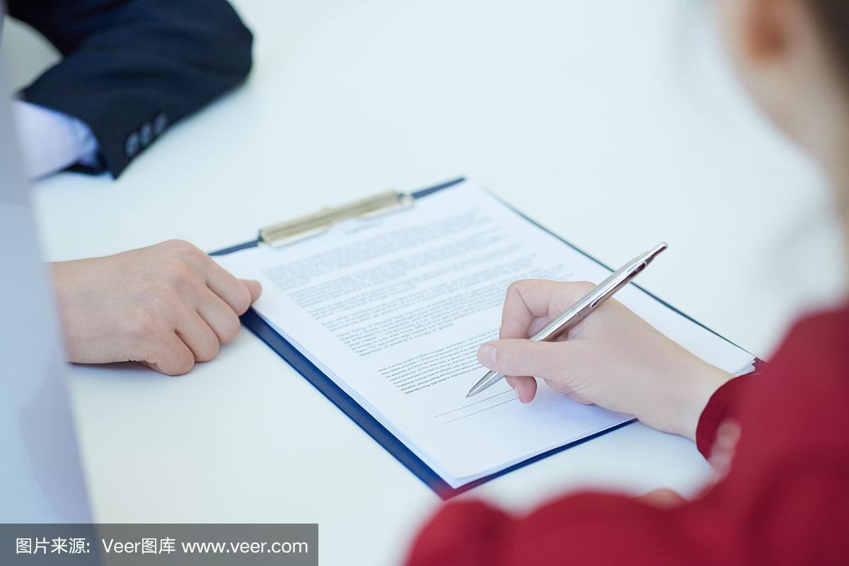 普通人坐在书桌前翻阅打印版保险合同的实拍图