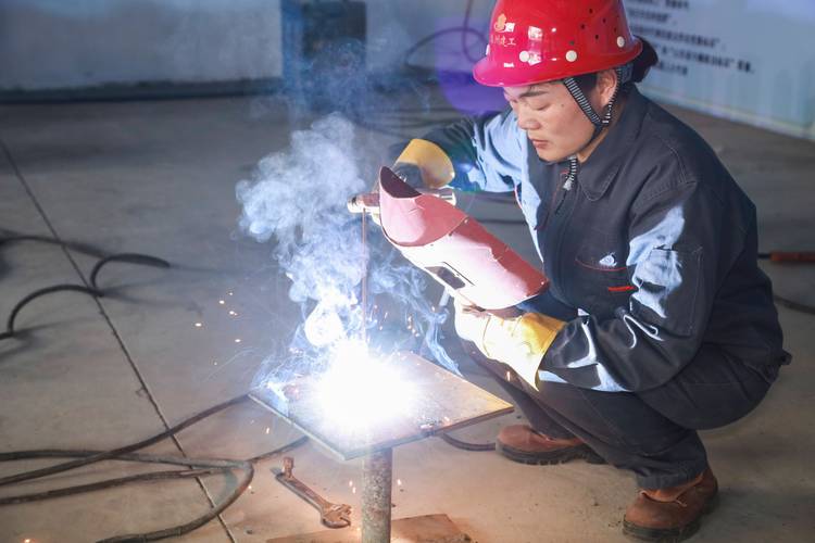 重工业车间老焊工带年轻学徒操作焊枪