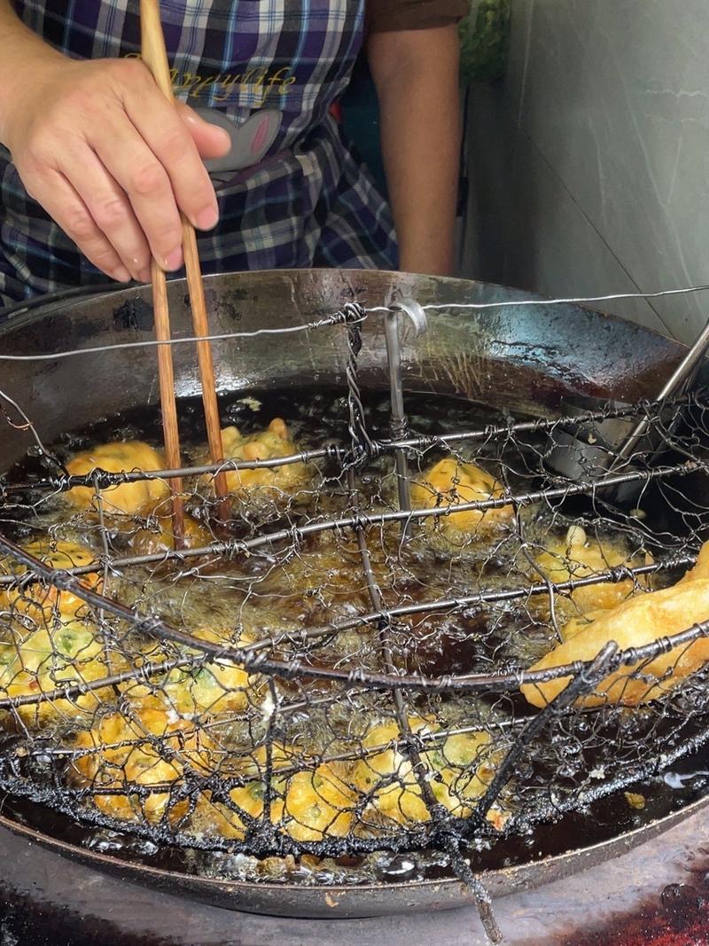 菜市场里热气腾腾的油墩子摊位,老板正在炸制