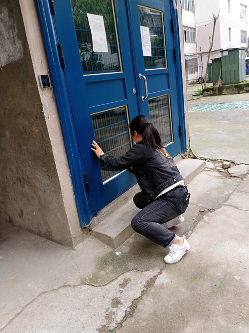 小学教师站在老居民楼单元门口敲门
