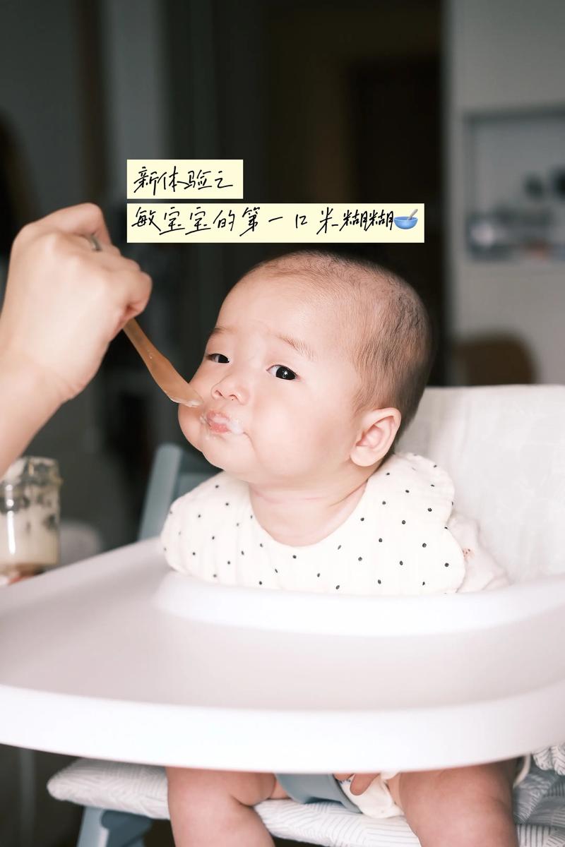 婴儿坐在实木宝宝餐椅上伸手抓陶瓷碗里的米糊