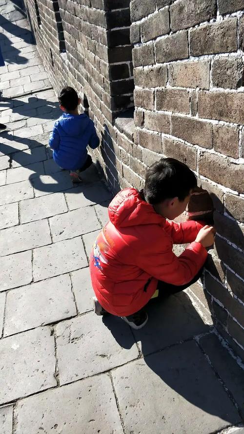 小朋友蹲在西安大雁塔城墙根摸古砖